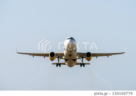 Passenger jet nearing runway, landing gear extended, illuminated landing lights signaling imminent touchdown during approach 130108779