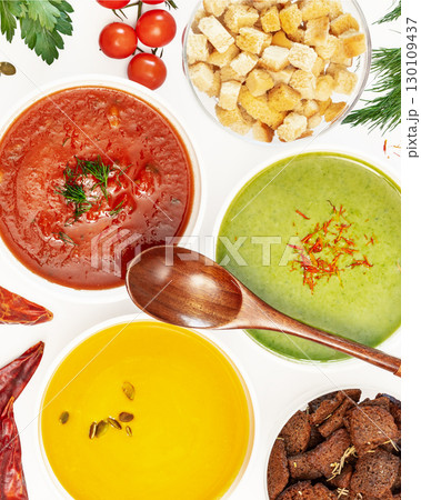 Food banner with set of different vegetable cream soups with wooden spoon on a white background with ingredients. Cozy meal, vegetarian healthy food. Top view Food banner with set of different vegetable cream soups with wooden spoon on a white background with ingredients. Cozy meal, vegetarian healthy food. Top view 130109437