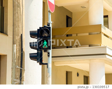 A traffic light showing green pedestrian symbol near a modern building. Concept of movement, urban mobility and everyday city rhythm. 130109517