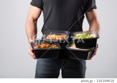 Man holding multiple takeout containers with a focus on healthy eating choices Man holding multiple takeout containers with a focus on healthy eating choices 130109618