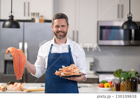 Hispanic man in kitchen with sea food. Mature man cook crab leg. Healthy food dieting. Man cook seafood. Fish menu with seafood. Man cooking crab claw and fish. Copy space Hispanic man in kitchen with sea food. Mature man cook crab leg. Healthy food dieting. Man cook seafood. Fish menu with seafood. Man cooking crab claw and fish. Copy space 130109638