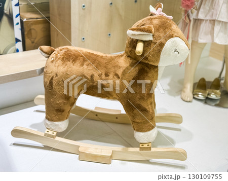 Plush rocking deer toy with wooden base in store. Childhood joy, play, and emotional comfort through imaginative activities. Plush rocking deer toy with wooden base in store. Childhood joy, play, and emotional comfort through imaginative activities. 130109755