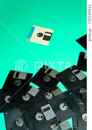 A collection of obsolete floppy disks, artifacts from the digital age of the 90s, arranged haphazardly on a turquoise background A collection of obsolete floppy disks, artifacts from the digital age of the 90s, arranged haphazardly on a turquoise background 130109812