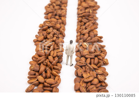 A metaphorical stock shot of a small figure in a suit between coffee beans 130110085