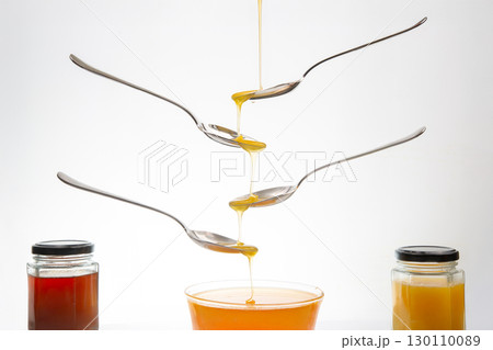 Fresh flower honey drips from a spoon into a spoon on a white background. Organic vitamin food. Fresh flower honey drips from a spoon into a spoon on a white background. Organic vitamin food. 130110089