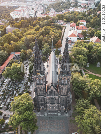 The stunning Vysehrad Basilica of St. Peter and St. Paul stands majestically at sunrise, surrounded by lush greenery and historic buildings in Prague, Czechia. 130110152