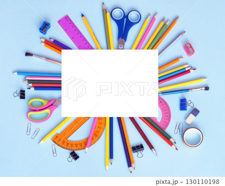 white sheet of paper and a school stationery around on a blue background 130110198
