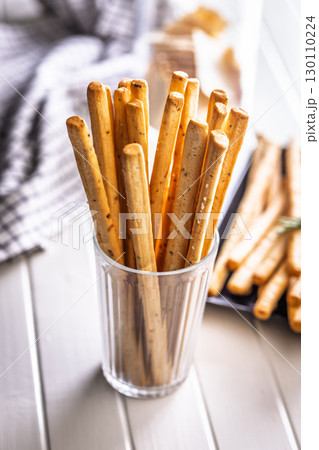 Crispy grissini breadsticks in cup on white table. 130110224