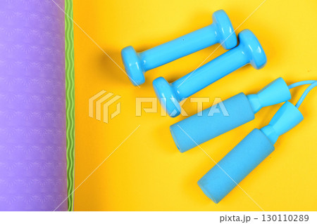 Shaping and fitness. Barbells and skipping rope on yoga mat Shaping and fitness. Barbells and skipping rope on yoga mat 130110289