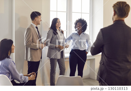 Multiracial business team standing together, listening to colleague, discussing company strategy. 130110313