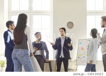 Confident businessman presenting ideas to colleagues while discussing strategy and brainstorming. 130110321