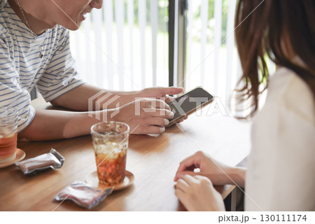スマホを見ながら笑顔で会話する男女 130111174