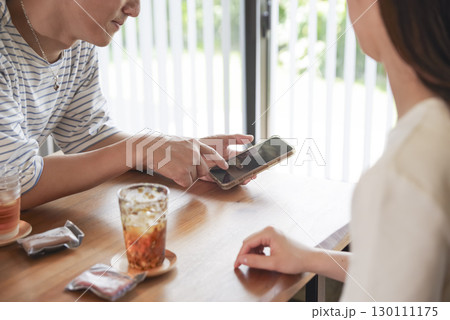 スマホを見ながら笑顔で会話する男女 130111175