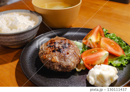 ハンバーグとトマト、ポテトサラダ、ご飯と味噌汁を添えた夕食 130111437