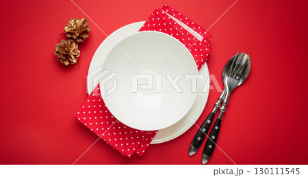 Christmas table setting decorated with pine cones and fir branches on red background 130111545
