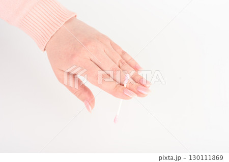 Pink cotton swab between fingers of young woman. 130111869