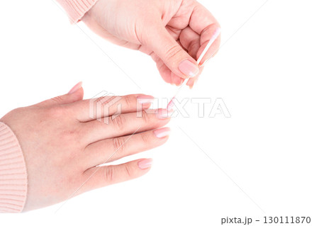 Female hands cleaning nails with manicure using pink cotton swab. 130111870