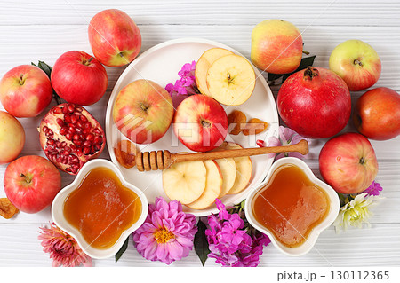 Jewish holiday Rosh Hashanah concept with apples, honey, pomegranate and flowers for greeting card, creative layout and template for Jewish New Year and Thanksgiving, autumn banner for design. 130112365