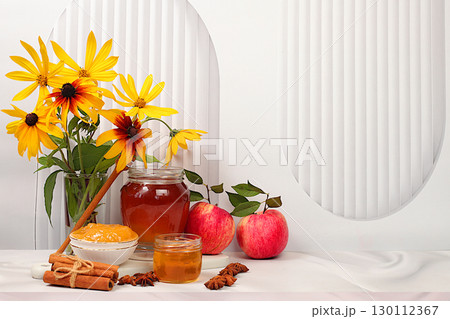 Autumn banner with honey, apples, pomegranates, flowers, dried fruits for holiday greeting, composition for Jewish holiday Rosh Hashanah with traditional symbols, creative layout for design, template. 130112367