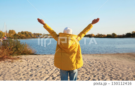 Happy woman on beach, enjoying amazing landscape, warm weather standing on sea coast 130112416