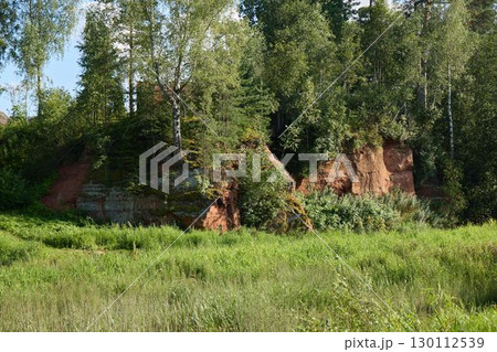 Serene and beautiful Landscape featuring a striking Red Rock Formation accompanied by Lush Greenery 130112539