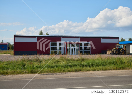 A newly constructed red commercial building located conveniently by the road for easy access 130112572