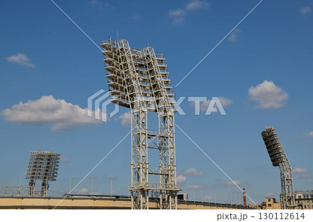 The illuminated floodlights of the sports stadium shine brightly against the clear sky 130112614