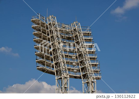 An Illuminated Sports Facility Lighting Tower Is Set Under a Clear Blue Sky Above Us An Illuminated Sports Facility Lighting Tower Is Set Under a Clear Blue Sky Above Us 130112622