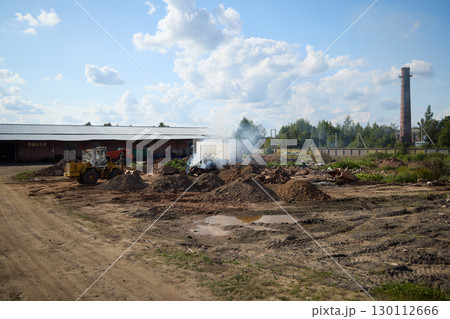A captivating industrial landscape filled with smoke, machinery, and human activity all around 130112666