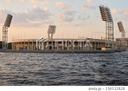 A breathtaking and stunning view of a beautiful sunset over a grand stadium situated by the water 130112828