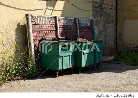 A vibrant urban scene shows green dumpsters in a cluttered alley, embodying city life A vibrant urban scene shows green dumpsters in a cluttered alley, embodying city life 130112965