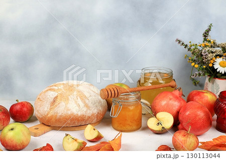 Autumn composition with apples, honey, pomegranate and candle. Harvesting concept, Jewish New Year Rosh Hashanah background, ecological food. Healthy eating, body detoxification, selective focus 130113044