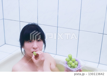お風呂に入りながらシャインマスカットを食べる若い女性 130113642