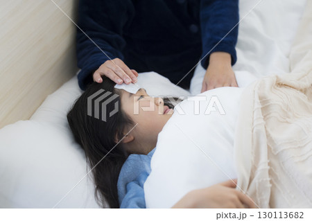 熱を出した小学生の女の子とお母さん 130113682