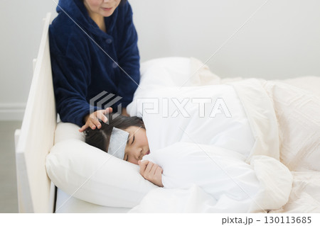 熱を出した小学生の女の子とお母さん 130113685