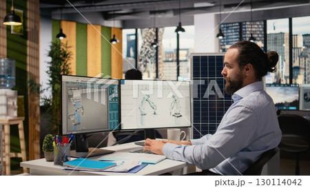 Sustainability RD expert uses CAD program on PC to design production lines for solar panel assembly. Worker runs simulation tools to enhance solar cells, accelerating clean energy adoption, camera A Sustainability RD expert uses CAD program on PC to design production lines for solar panel assembly. Worker runs simulation tools to enhance solar cells, accelerating clean energy adoption, camera A 130114042