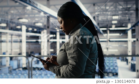IT expert monitors server farm activity using tablet while walking on industrial platform. Data center system administrator reviews rigs tests results to ensure systems are working correctly, camera B IT expert monitors server farm activity using tablet while walking on industrial platform. Data center system administrator reviews rigs tests results to ensure systems are working correctly, camera B 130114078