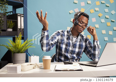 Tired telemarketing agent holding his glasses, feeling overwhelmed when managing customer concerns at work. Company secretary seated at his desk, appearing frustrated as he solves project tasks. Tired telemarketing agent holding his glasses, feeling overwhelmed when managing customer concerns at work. Company secretary seated at his desk, appearing frustrated as he solves project tasks. 130114079