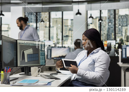 Product designer in office creates compact solar device for renewable energy projects. Engineer in modern workplace designs solar gadget prototype to reduce environmental impact 130114289