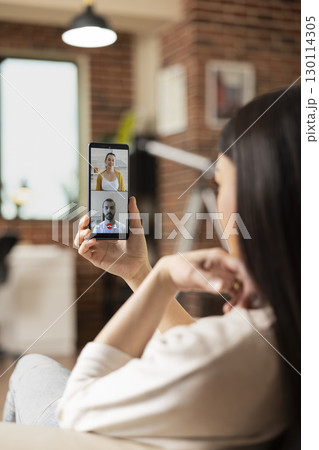 Woman entrepreneur holds cellphone, having virtual meeting with business partners, discussing startup strategies. Female manager using mobile device for video call with remote caucasian employees. Woman entrepreneur holds cellphone, having virtual meeting with business partners, discussing startup strategies. Female manager using mobile device for video call with remote caucasian employees. 130114305