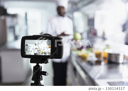 African american chef filming a culinary master class for beginners, providing essential cooking skills and other techniques. Remote course held in a kitchen, making gourmet training on the web. African american chef filming a culinary master class for beginners, providing essential cooking skills and other techniques. Remote course held in a kitchen, making gourmet training on the web. 130114317