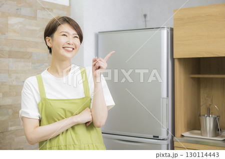 冷蔵庫を開けるエプロン姿の女性 130114443