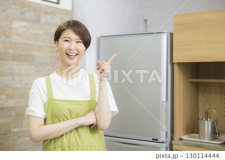 冷蔵庫を開けるエプロン姿の女性 130114444