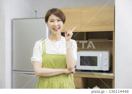 冷蔵庫を開けるエプロン姿の女性 130114448