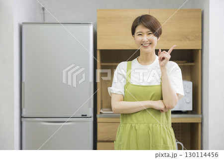 冷蔵庫を開けるエプロン姿の女性 冷蔵庫を開けるエプロン姿の女性 130114456