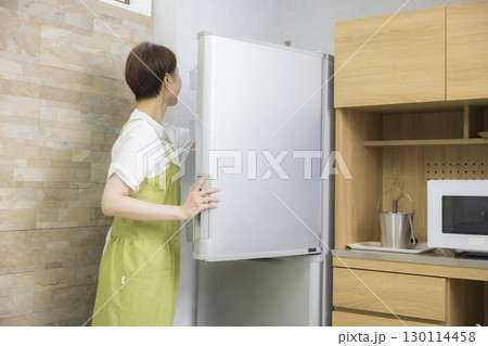 冷蔵庫を開けるエプロン姿の女性 冷蔵庫を開けるエプロン姿の女性 130114458