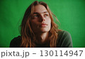 A person with long hair looking thoughtful with a green backdrop enhancing the friendly vibe 130114947