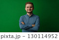 An approachable individual with a warm smile showcasing a casual outfit against a green setting 130114952