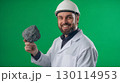 A smiling geologist pointing to a volcanic rock in their hand 130114953