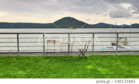 A Beautiful and Serene Lakeside View Featuring Tables and Chairs for Relaxation and Enjoyment A Beautiful and Serene Lakeside View Featuring Tables and Chairs for Relaxation and Enjoyment 130115981